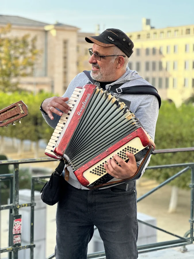 A street musician playing a red accordion outdoors